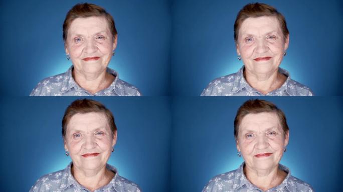 蓝色背景工作室微笑的老年妇女肖像。白人善良的祖母看着相机。