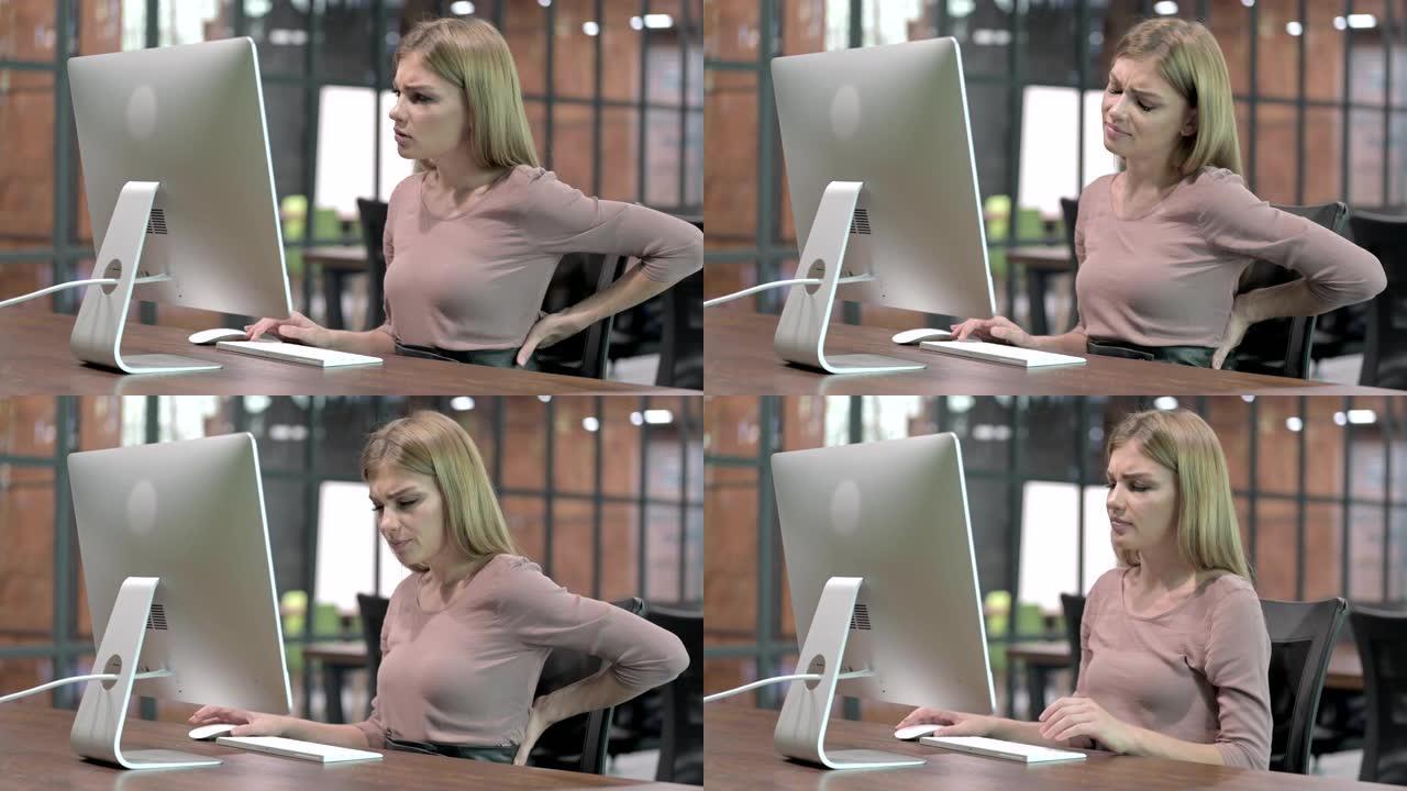 在电脑上工作时背部疼痛的疲惫女人