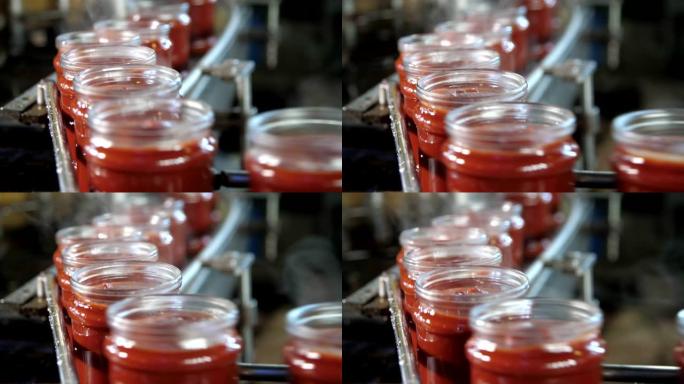 番茄工厂的加热番茄酱罐在没有盖子的金属线上