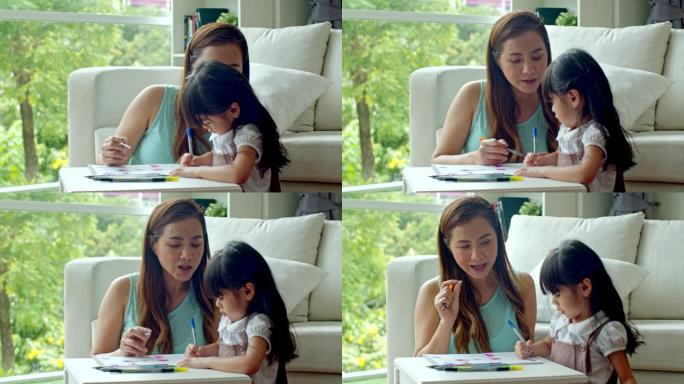 年轻的母亲教可爱的女儿在纸上画画