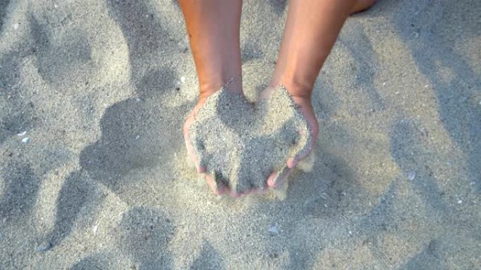 双手在海滩上握着和洒沙