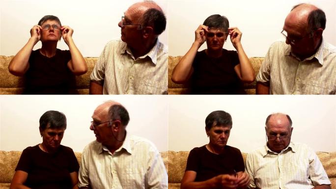 一对老年夫妇坐在家里的沙发上，试着戴眼镜看视力，互相咨询。