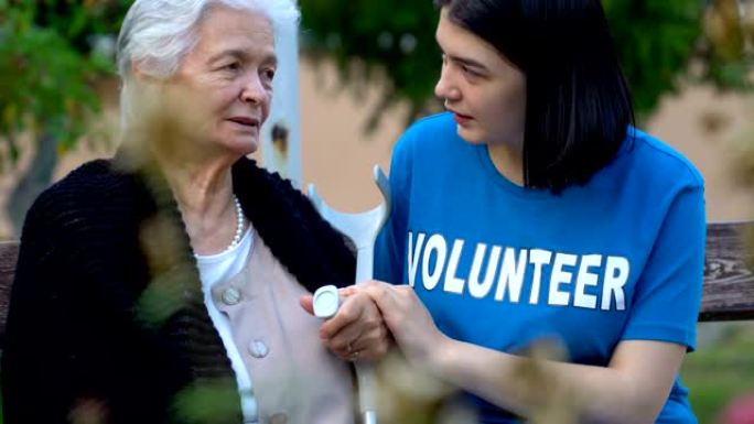 年轻的志愿者握着老年女士的手
