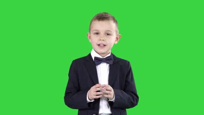严肃的小男孩在绿色屏幕上向相机讲话，色度键