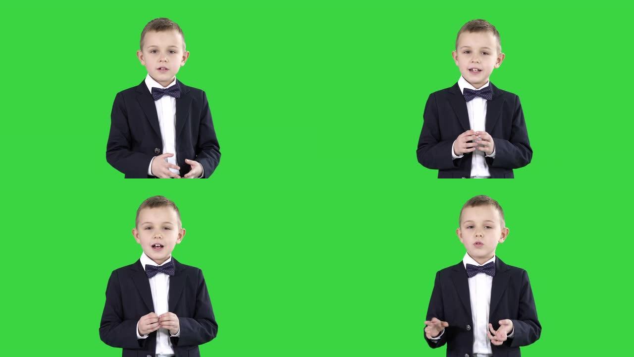 严肃的小男孩在绿色屏幕上向相机讲话，色度键