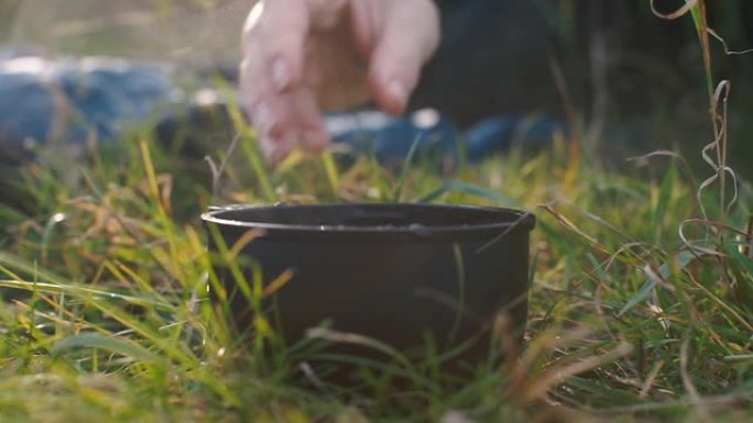 游客在草地上放一个装有热茶的保温杯。