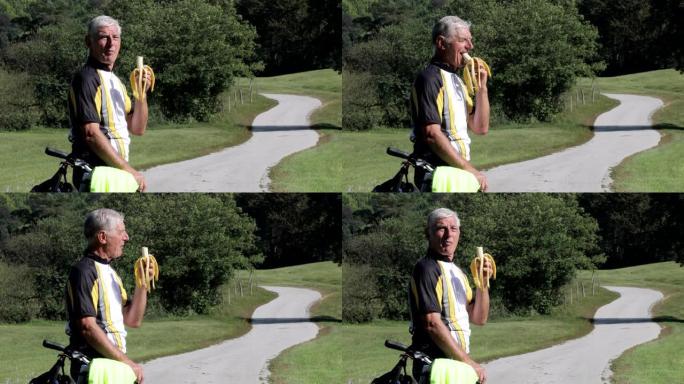 高级成人自行车手在乡下吃香蕉的侧视图
