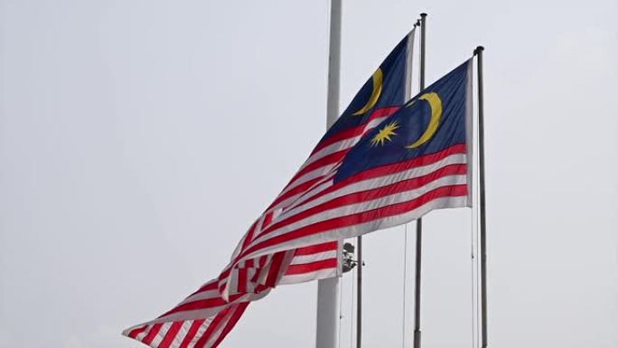 三面马来西亚国旗在多云的天空中飘扬