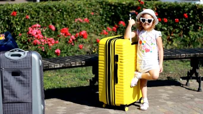 带着黄色大手提箱的女婴游客。等待旅行的孩子。