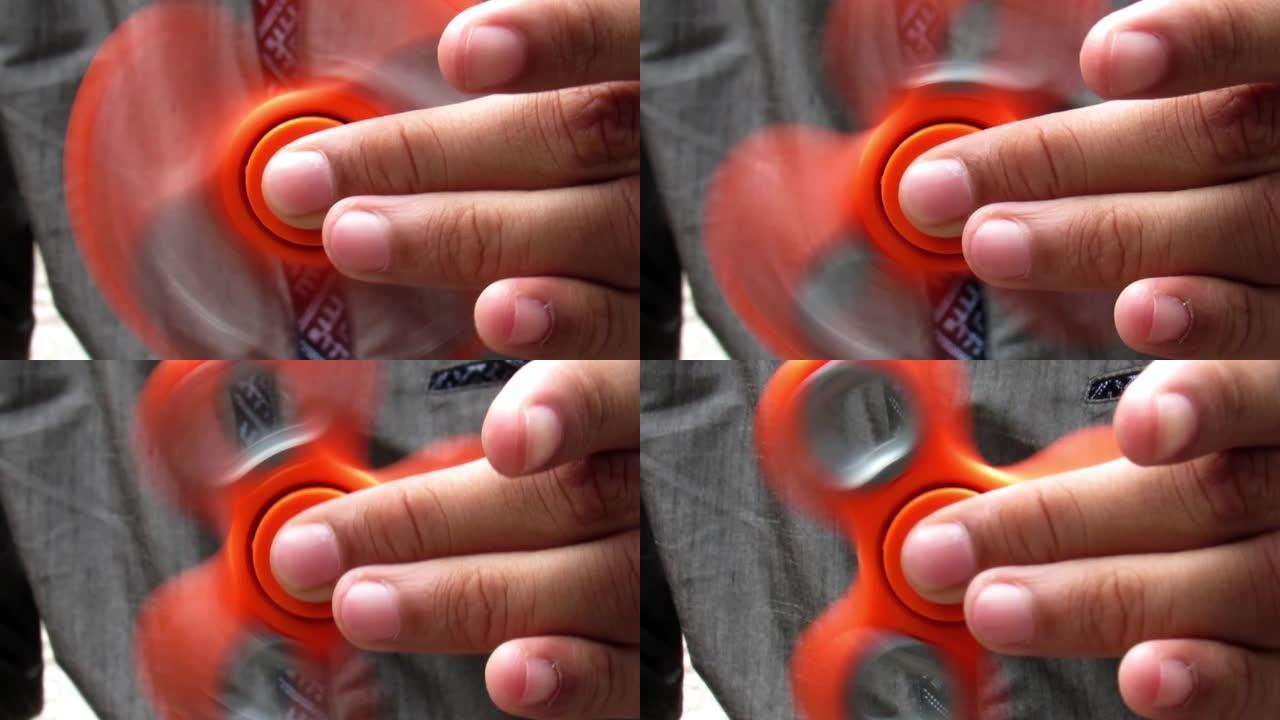一个年轻的高加索男孩玩橙色烦躁的旋转器的手的特写。