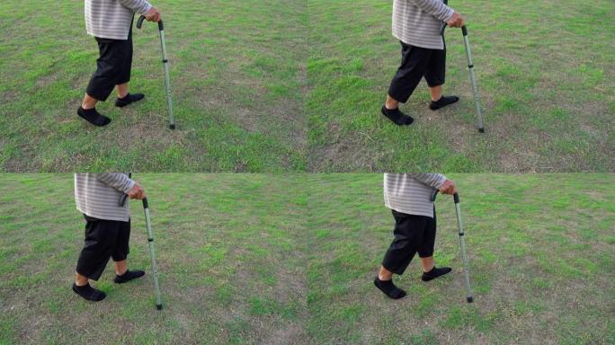 高级女子腿在草地上用手杖走路