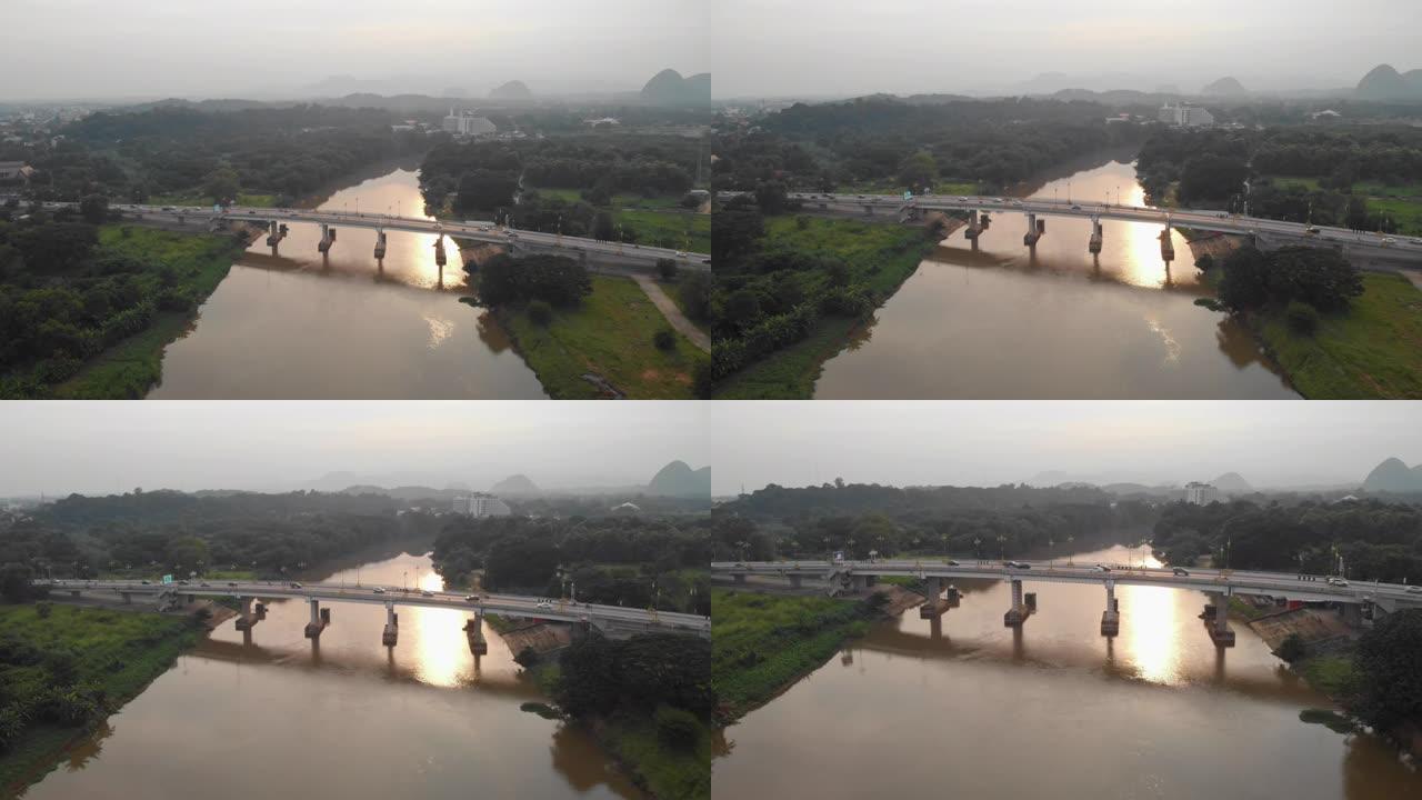 无人机低矮向下移动，过河桥，汽车，鸟瞰交通过河桥，清莱，泰国，亚洲桥，山，树。阳光，早晨，东南亚，日