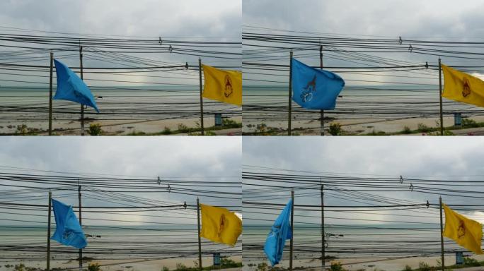 阴天在海边挥舞旗帜。阴天沿海岸悬挂泰国及王室彩旗。背景上杂乱的电线。国家和泰国民族的象征。