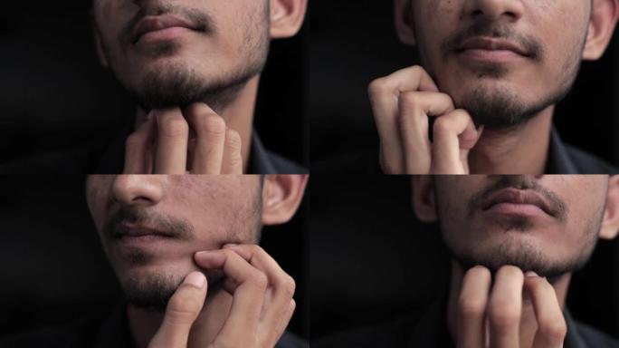 胡子男人的特写镜头被隔离在黑色上，用他的手瘙痒他的胡子，有很大的空间作为广告的理想用途。