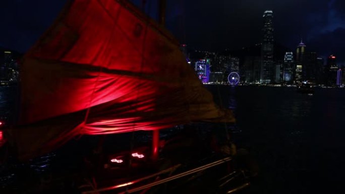 在香港天际线的夜晚，红帆舢板船