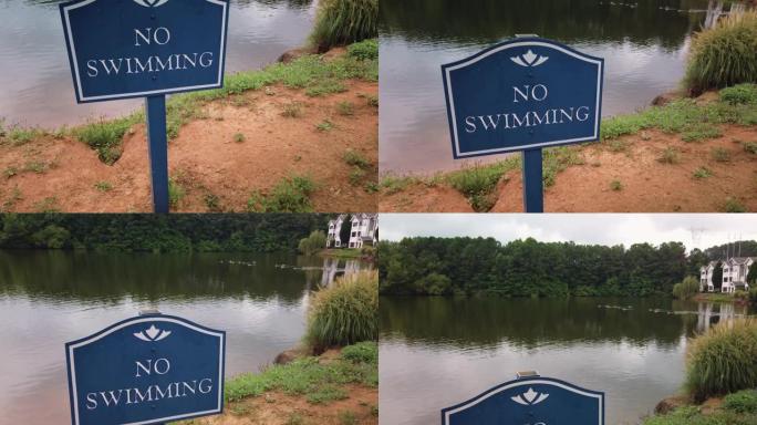 一个蓝色的禁止游泳标志贴在一个安静的男子在郊区房屋开发项目的池塘前。