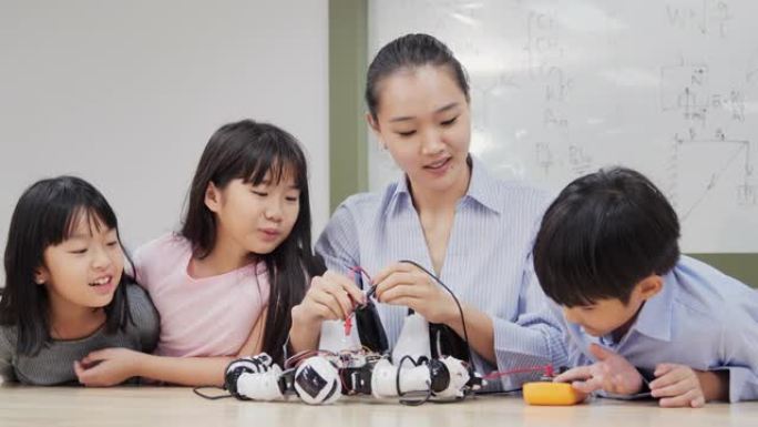 机器人班的学生和老师。顾问向学生解释她的机器人项目。