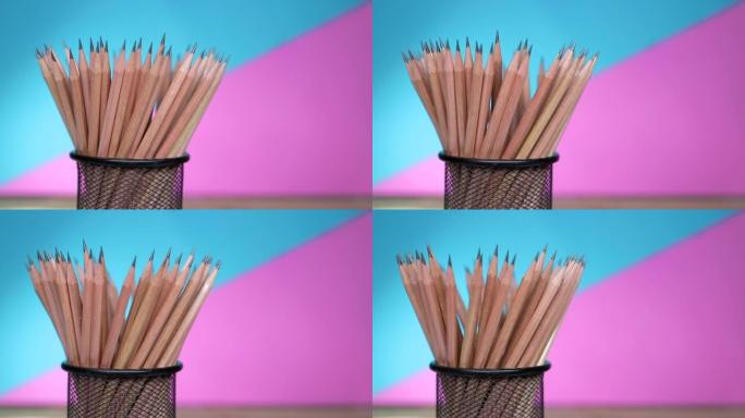 架子上的木制铅笔在蓝色和粉红色背景上旋转