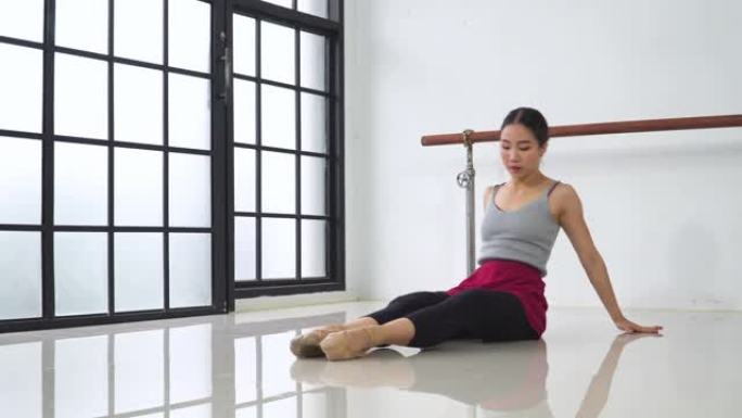 侧视图: 年轻的芭蕾舞女坐着时伸展腿