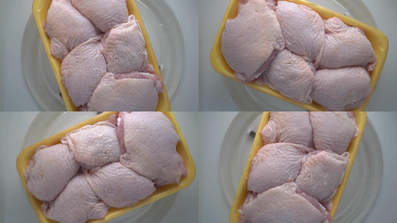 食物托盘中的新鲜生鸡腿在微波俯视图中旋转。