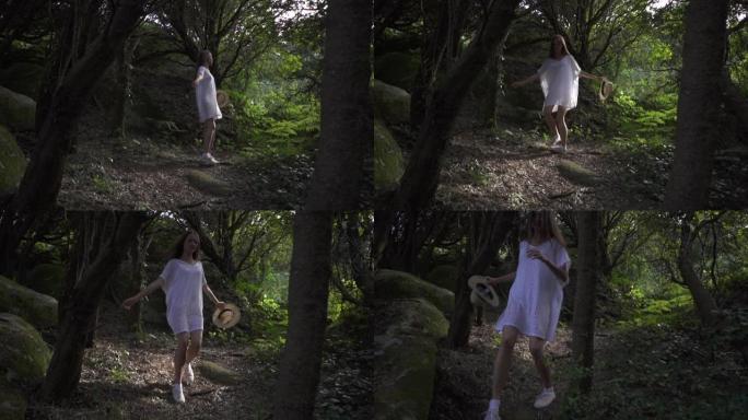 快乐的女孩旅行者带着草帽在魔法森林里奔跑，带着高大的绿色树木、植物和大神秘的石头。爱丽丝梦游仙境。