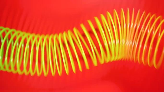 复古复古抽象背景。彩虹色的弹簧以波浪状的图案在红色背景上移动。紧身玩具。彩虹螺旋弹簧运动波浪明亮美丽