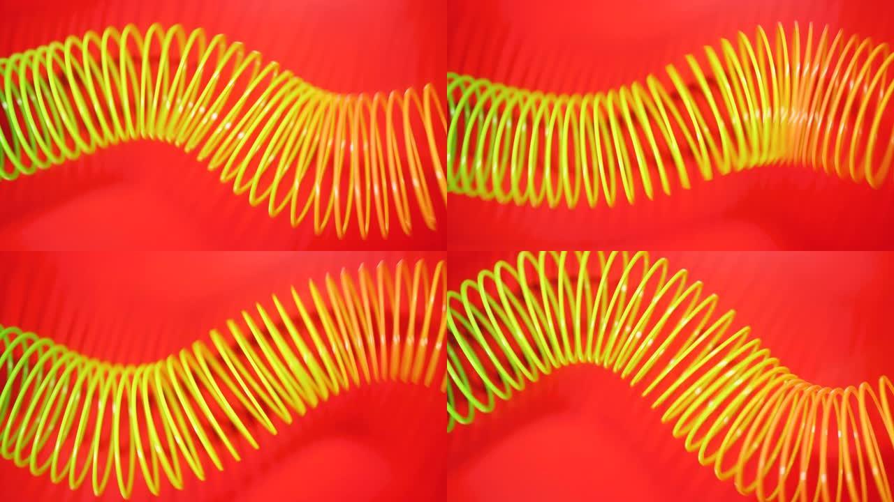 复古复古抽象背景。彩虹色的弹簧以波浪状的图案在红色背景上移动。紧身玩具。彩虹螺旋弹簧运动波浪明亮美丽