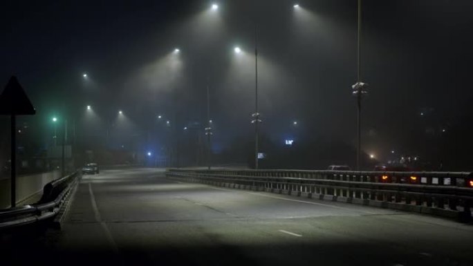 汽车晚上在潮湿的雾气路上行驶。危险的夜间驾驶。高速公路上的灯亮着