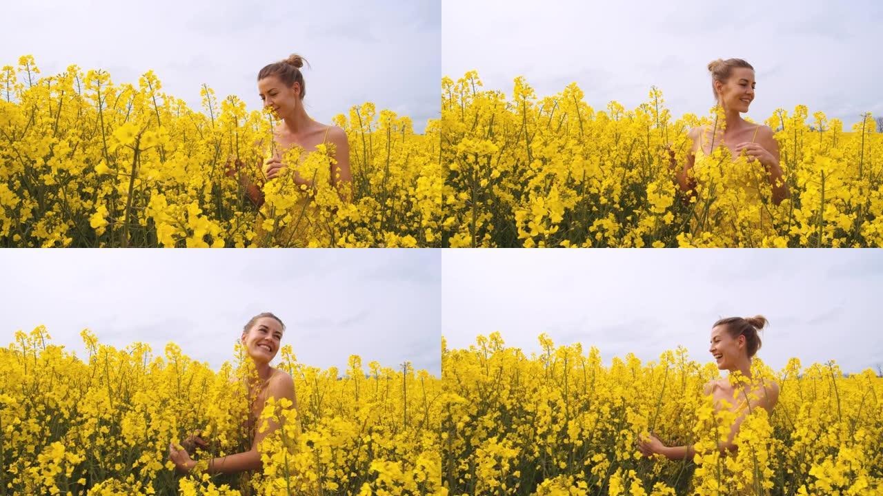 穿着黄色连衣裙的美女，闻到并拥抱着一束油菜花