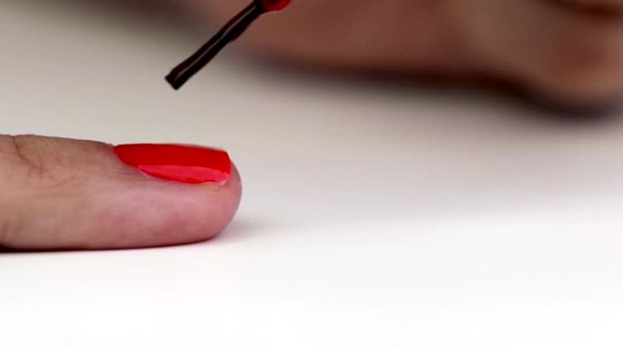 妇女在手指上涂抹红色指甲油