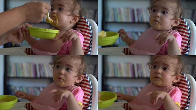 UHD视频女婴坐在喂奶椅上吃婴儿食品