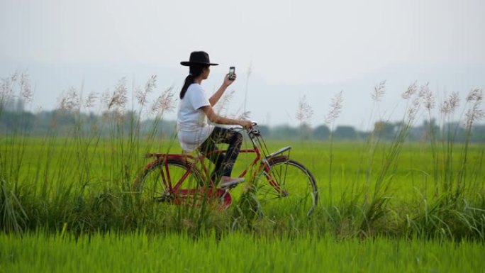 亚洲女子骑自行车在稻田里自拍