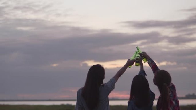 一群年轻的亚洲女性快乐的朋友在大自然中露营，一起喝啤酒和碰杯玩得开心。和朋友一起喝啤酒，一边看风景。