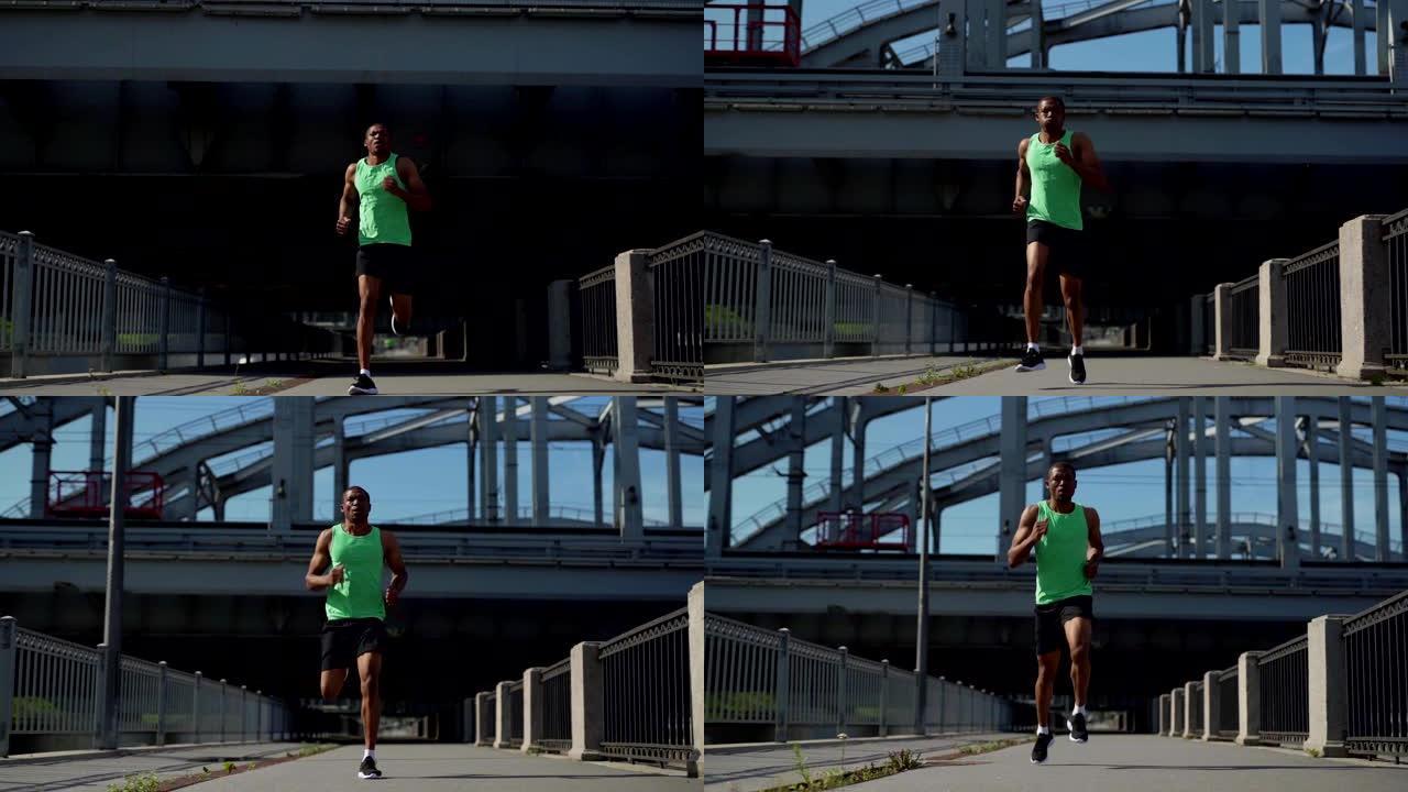 全程慢动作镜头坚定的男非洲运动员在绿色背心和运动短裤跑下城市大桥在马拉松训练