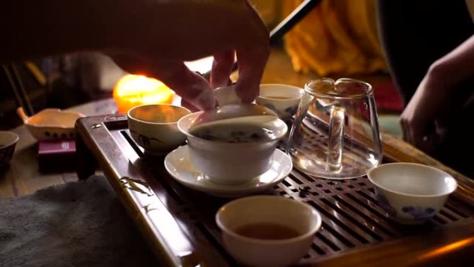 在中国传统茶道中，一名男子用木制功夫茶桌和茶具从粘土茶壶中倒出红茶