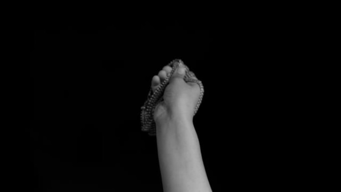 一只女性的手站起来，在黑色背景上隔离着一堆payals，脚链，脚踝链，脚踝手镯或脚踝绳。