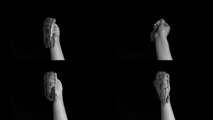 一只女性的手站起来，在黑色背景上隔离着一堆payals，脚链，脚踝链，脚踝手镯或脚踝绳。