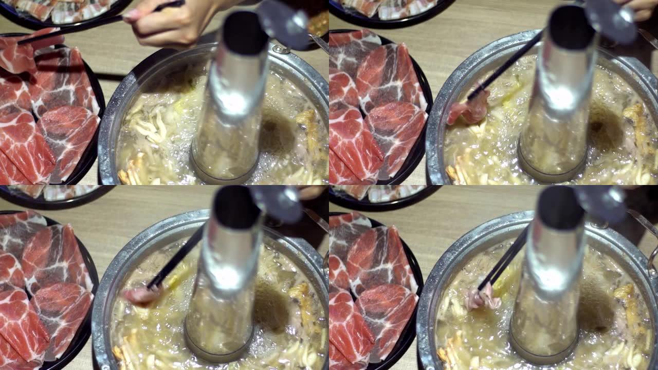 牛肉生肉用筷子固定。带有甜甜圈形黄铜锅的火锅。