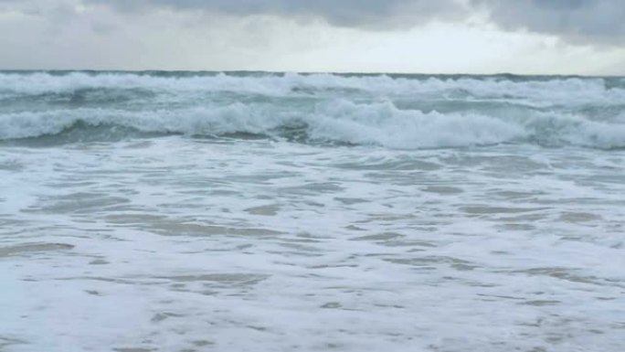 海水的慢动作，大海浪在雨云天空下溅起海滩。