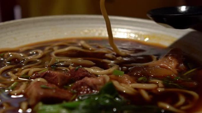 女人用棍子吃牛肉面的慢动作。中式餐厅