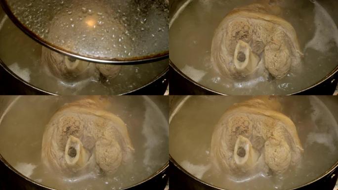 猪腿在骨头上的指节在金属锅中煮沸的肉汤中煮熟。