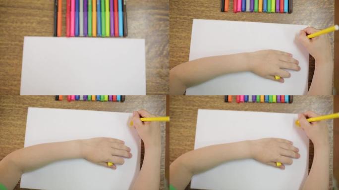 孩子用黄色的毡尖笔在白纸上画画。儿童用毡尖笔绘制特写。这个男孩画了一个黄色的太阳。