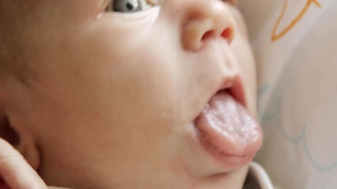 满足的新生婴儿用蓝色的大眼睛看着镜头，脸部特写