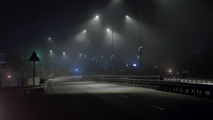 汽车晚上在潮湿的雾气路上行驶。危险的夜间驾驶。高速公路上的灯亮着