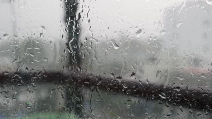 强烈的雨水冲向窗户玻璃并向下流动，关闭。雨季玻璃背景上的雨滴。4k