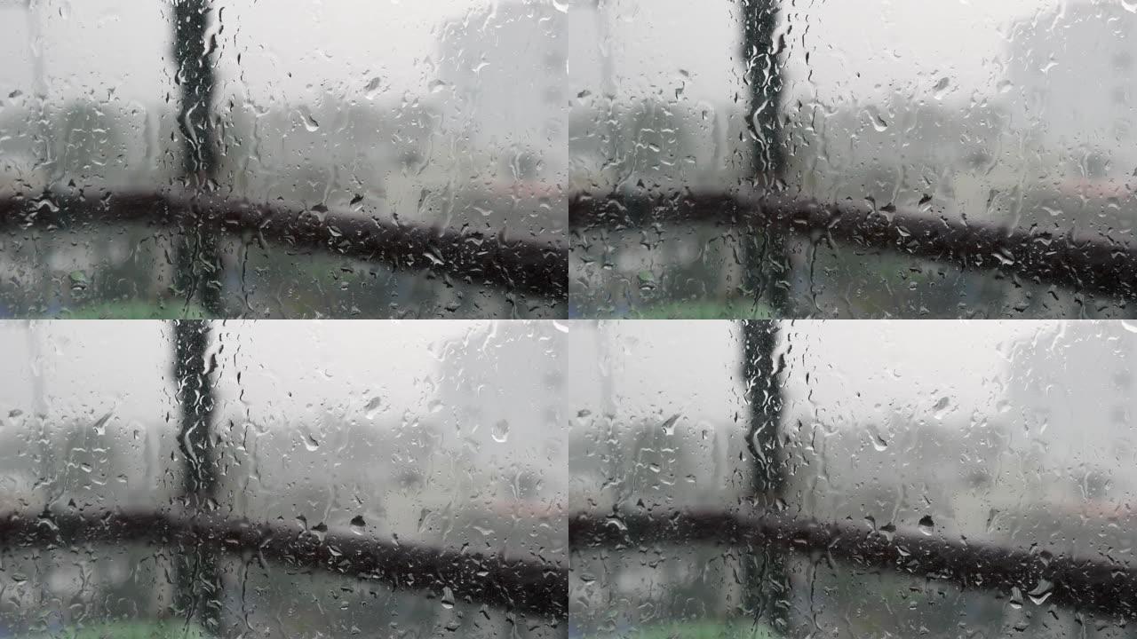 强烈的雨水冲向窗户玻璃并向下流动，关闭。雨季玻璃背景上的雨滴。4k