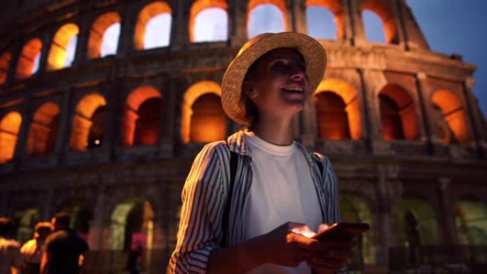 戴着帽子的迷人女游客站在罗马历史名胜附近嘲笑手机社交网络的搞笑内容