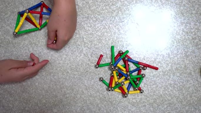 小孩子在室内玩许多彩色磁铁玩具和铁球。