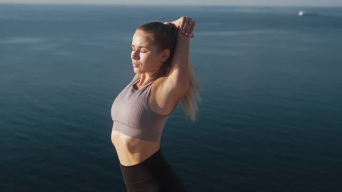 女人早上做运动和伸展运动，可以看到大海，慢动作