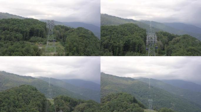 鸟瞰图云山夏季林木间移动缆车小屋。缆车在多云的山峰背景下在山区度假胜地的绳索上行驶